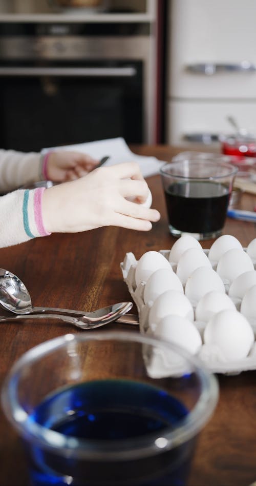 A Girl And A Boy Soaking Eggs On A Bowl Of Liquid Colorings