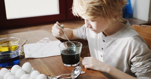 Soaking And Lifting An Egg From A Bowl Of Green Liquid Coloring