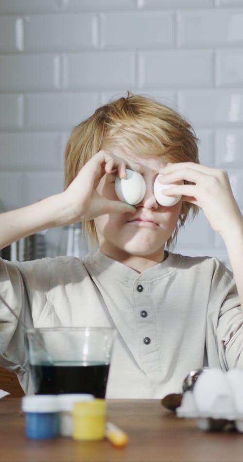 A Boy Playing With Eggs By Putting It Over His Eyes