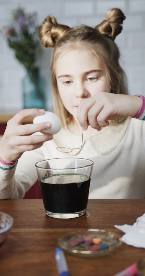 A Girl Soaking A White Egg On A Bowl Of Liquid Coloring