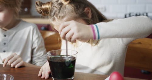 A Girl Stirring An Egg Inside A Bowl Of Color Green Liquid For Coloring