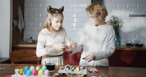 A Girl And A Boy Teaming Up To Decorate Ester Eggs