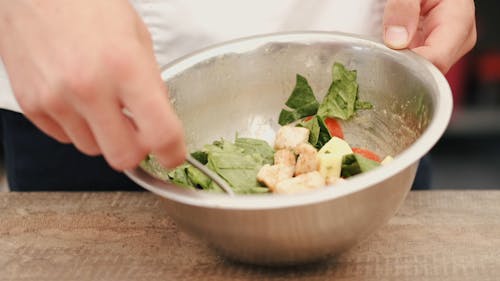 Person Mixing Vegetable Salad In A Stainless Bowl