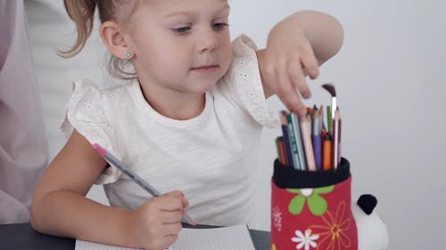 A Young Girl Choosing The Pencil Color To Use