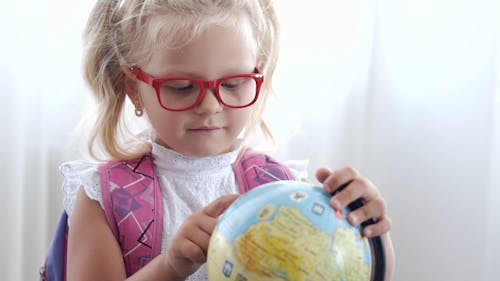 A Young Girl Using A Globe Search For A Location