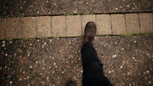 A Person Waking On A Pebblecrete Path