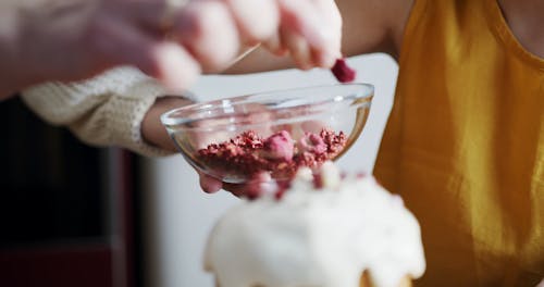 A Mother Teaching Her Daughter How To Put Toppings On Their Cake