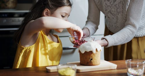 A Girl Is Placing Topping On A Cake