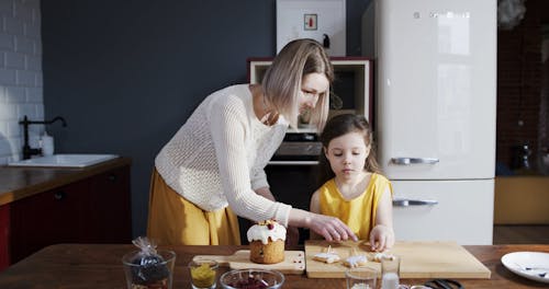 A Mother And Daughter Teaming Up To Finish Decorating A Homemade Easter Cake