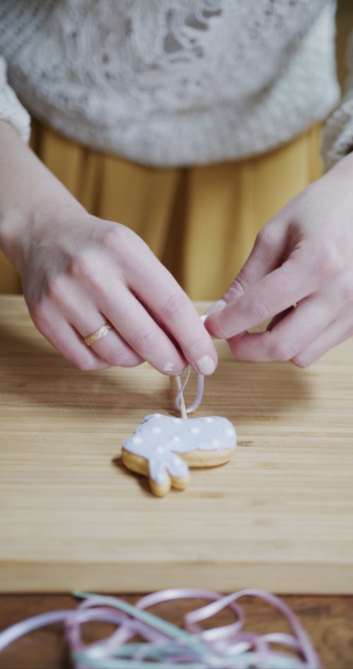 A Woman Tying a Ribbon On The Stick Of An Easter Bunny Cake Decor