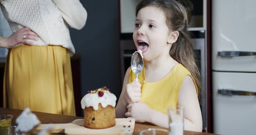A Girl Leaking With Her Tongue The Left Over Icing On A Spoon