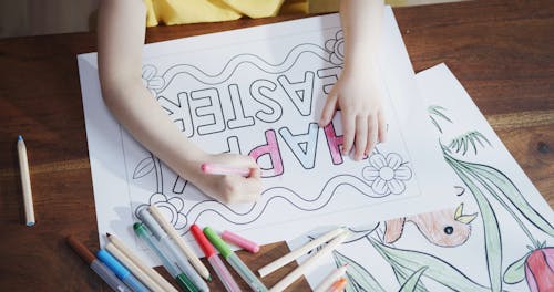 A Girl Coloring A Happy Easter Poster Using Colored Pens