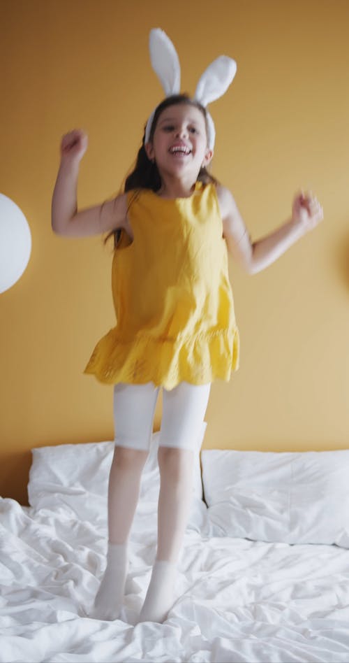 A Young Girl Jumping Up And Down On A Bed