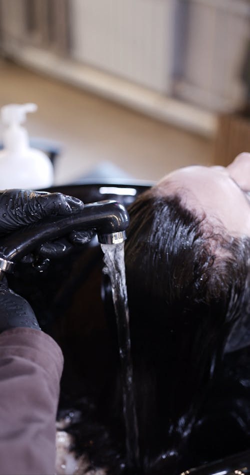 Wetting A Woman's Hair Over A Basin Before Cutting