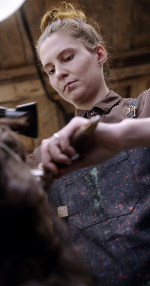 A Hairdresser Curling A Woman's Hair With Brush And Blow Dryer