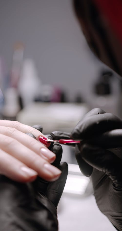 Applying Red Color Nail Polish On A Person Fingernails