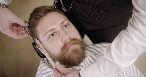 A Barber Trimming A Man's Side Beard