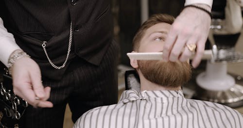 A Barber Trimming A Man's Beard