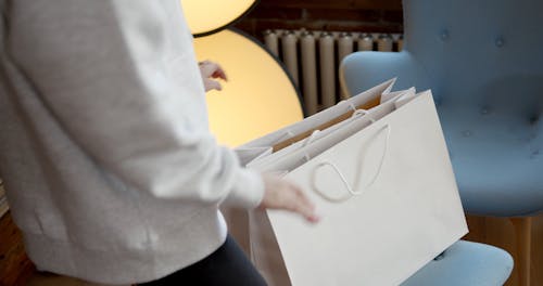 A Woman Checking Out Shopped Clothes Fro The Paper Bags