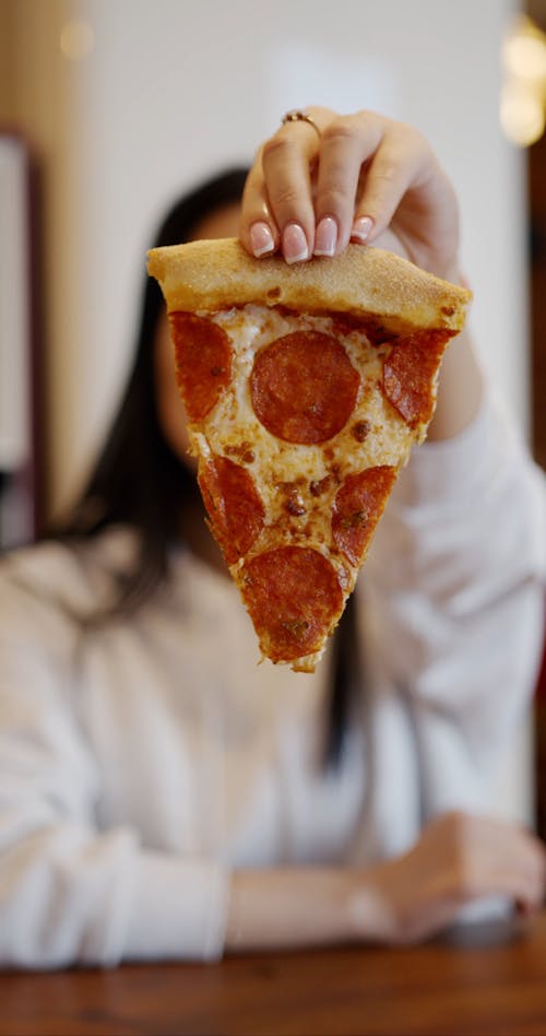 A Woman Eating A Slice Pepperoni Pizza