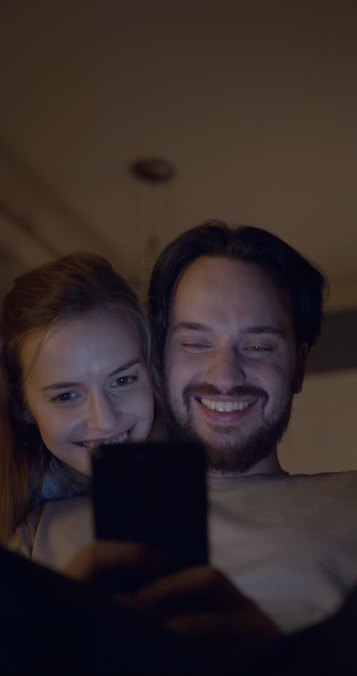 A Couple In Smiles While Looking Something On A Cellphone