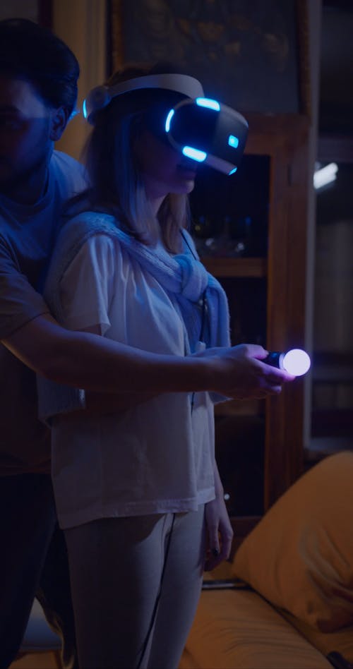 A Man Assisting His Wife In Playing A Virtual Reality Game