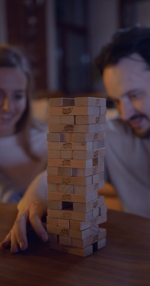 A Couple Playing A Game Of Wooden Blocks In Their Living Room