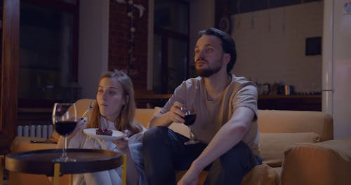 A Couple Having A Dessert And A Glass Of Wine While Relaxing In Their Living Room