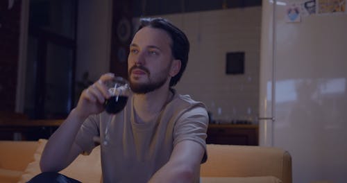 A Man Having A Glass Of Wine While Watching A Television