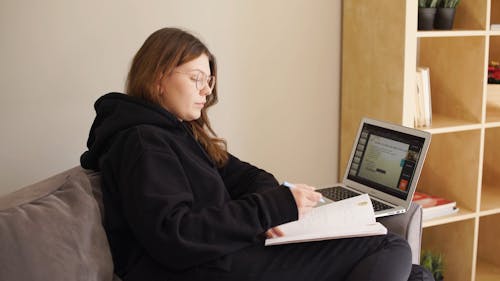 Woman Studying while Sitting on a Sofa