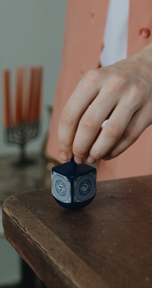 A Person Spinning A Top Toy Over A Wooden Table