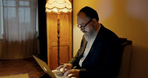 An Elderly Man Writing By Typing On A Laptop Keyboard