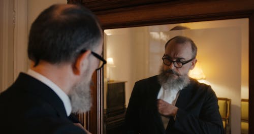 A Jewish Man Looking Himself At A Mirror Putting On His Kippah 