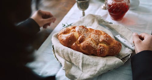 A Man Slicing A Challah Bread With Knife