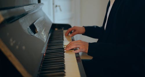 A Man Playing A Piano With His Partner Coming To Listen