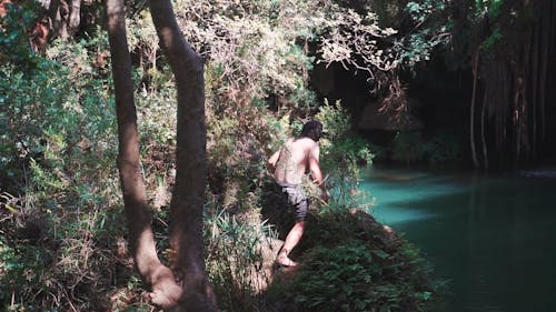 A Man Jumping On A Hidden Water Pond Inside The Forest