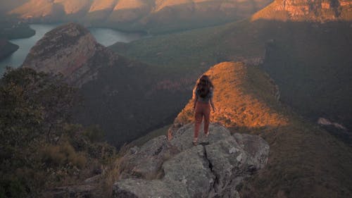 A Woman Standing on the Edge of a Cliff Enjoying the View