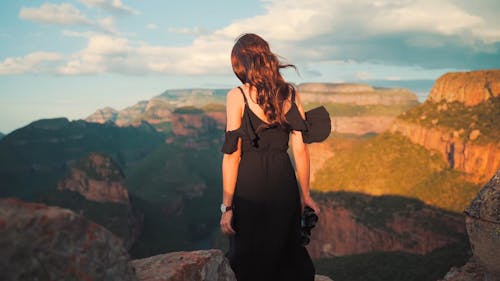 A Woman Walking Towards the Cliff with Binoculars
