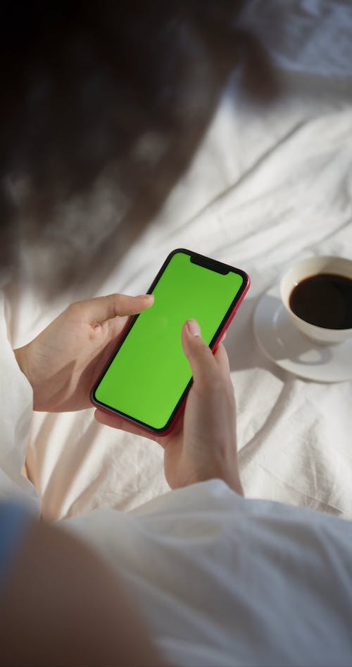 A Woman Using Her Cellphone While In Bed