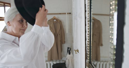 A Woman Putting On A Hat And A Trench Coat