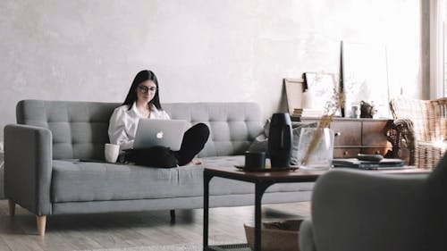 A Woman Drinking Coffee while Typing on her Laptop