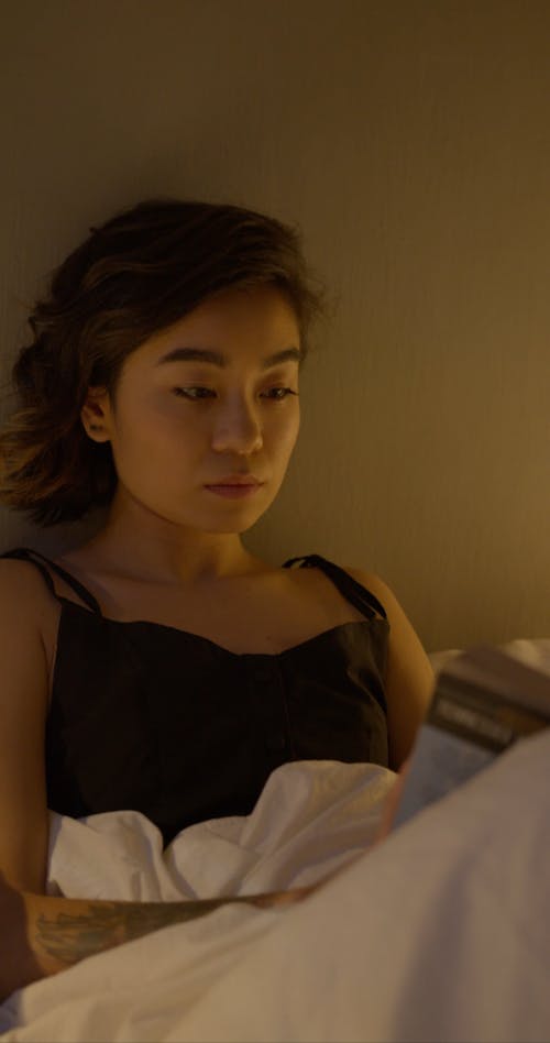 A Woman Reading a Book Before Going To Sleep