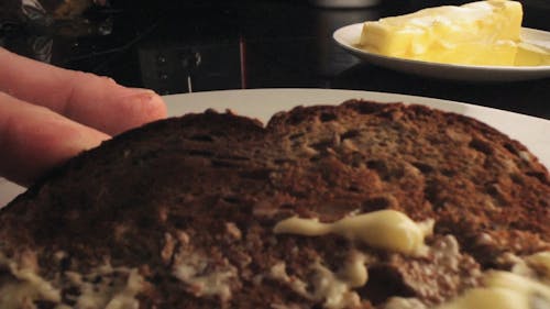 A Person Spreading Butter in a Piece of Bread