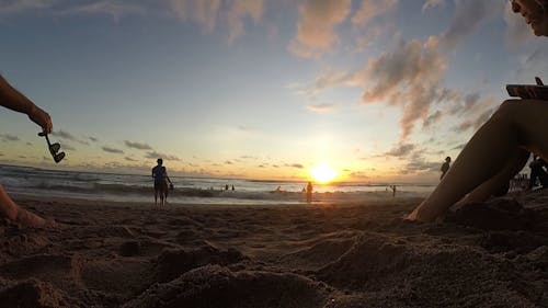 People Flocking A Beach At Sunset