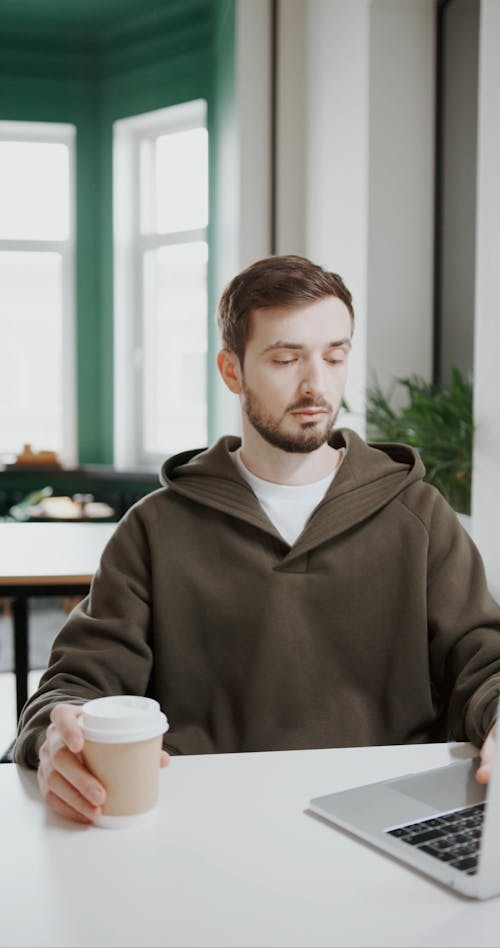 A Man Working On His Laptop While Drinking Coffee