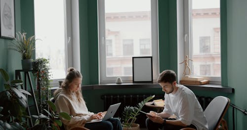 A Couple Using Their Gadgets Working At Home