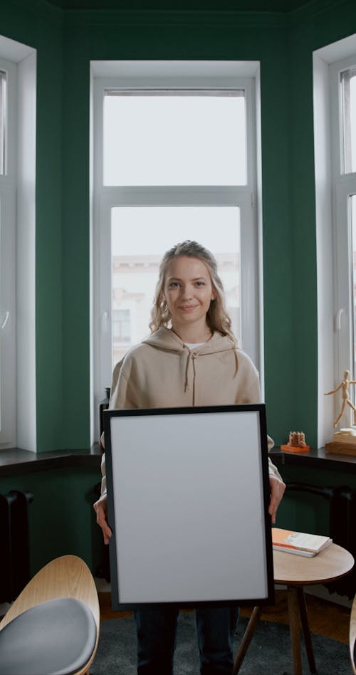 A Woman Holding A Black Frame With Blank Image In Front Of Her Face