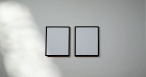 Two Empty Picture Frames Hanging On A Wall