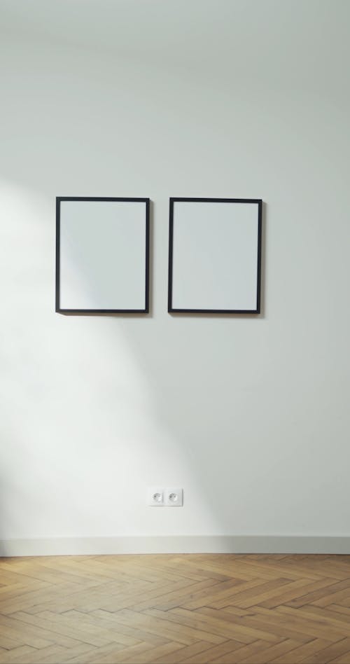 A Man Walks Across A Wall Where Two Photo Frames Are Hanging