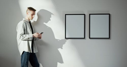 A Man Talking On His Phone While Leaning On A Wall 
